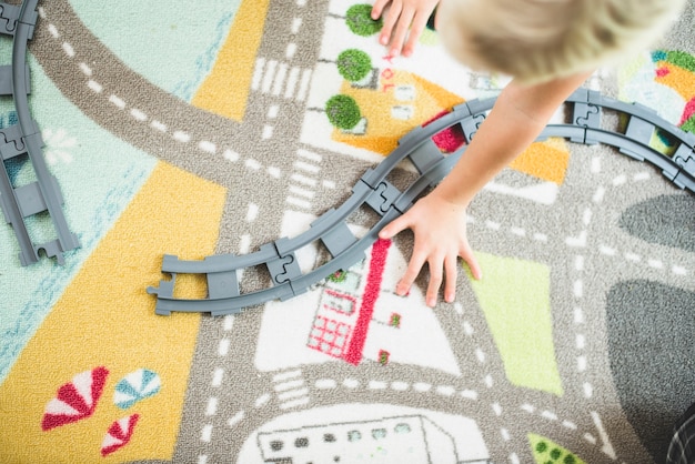 Vista superior de niño jugando con las vías de un tren