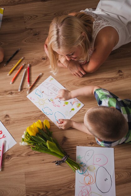 Vista superior de niño señalando un dibujo a su madre