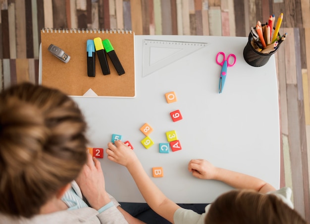 Vista superior del niño y el tutor aprendiendo sobre números y letras