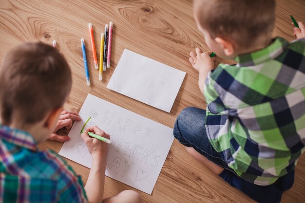 Vista superior de niños preparando un dibujo para el día de la madre