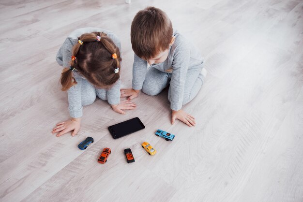 Vista superior. Niños que usan aparatos digitales en casa. Hermano y hermana en pijama miran dibujos animados y juegan juegos en su tableta tecnológica