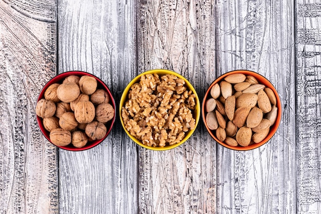 Foto gratuita vista superior de nueces y almendras en cuencos en madera horizontal