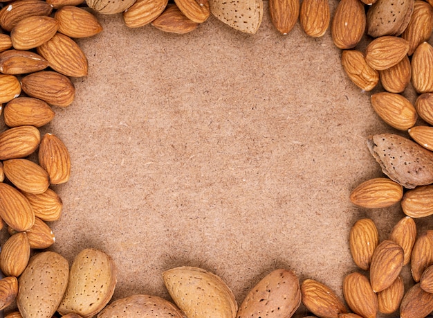 Vista superior de nueces almendras sobre fondo de textura de papel viejo con espacio de copia