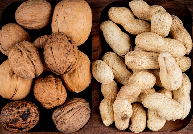 Vista superior de nueces cacahuetes con cáscara y nueces enteras sobre fondo de madera