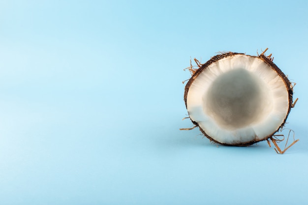 Una vista superior de nueces de coco en rodajas lechosas frescas suaves aisladas en el azul hielo