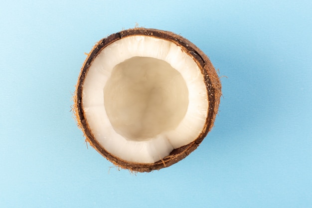 Una vista superior de nueces de coco en rodajas lechosas frescas suaves aisladas en el azul hielo