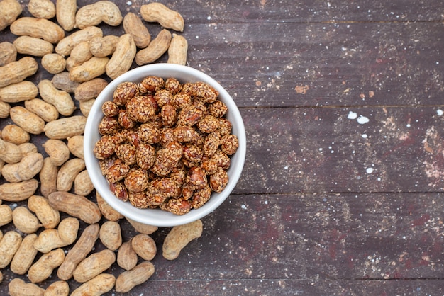 Foto gratuita vista superior de nueces dulces junto con cacahuetes en el escritorio de madera nuez bocadillo dulce de maní