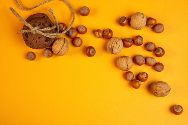 Vista superior de nueces enteras y avellanas y galletas de avena atadas con una cuerda en amarillo