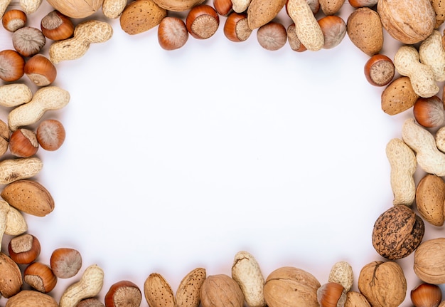 Vista superior de nueces mixtas en cáscara de avellanas cacahuetes nueces y almendras sobre fondo blanco con espacio de copia