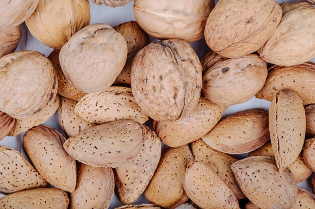 Vista superior de nueces mixtas en cáscara de nueces y almendras sobre fondo blanco.