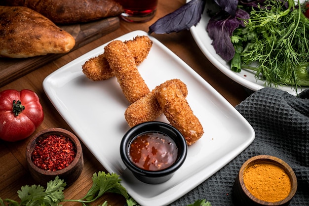 Vista superior de nuggets fritos y polvo de cúrcuma ketcup y pimiento rojo en un tazón pequeño verde en un plato blanco