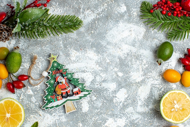 Vista superior ornamento del árbol de Navidad cortar limones feijoas en el espacio libre de la mesa gris