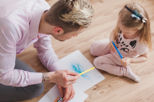 Vista superior de padre dandole un lápiz a su hija