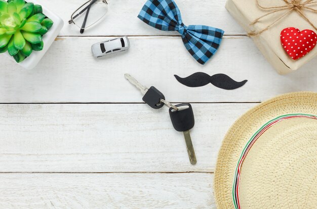 Vista superior Padre feliz day.Key con el coche para regalo a father.accessories con corazón rojo, bigote, corbata de la vendimia, presente, sombrero y árbol sobre fondo de madera blanca rústica.