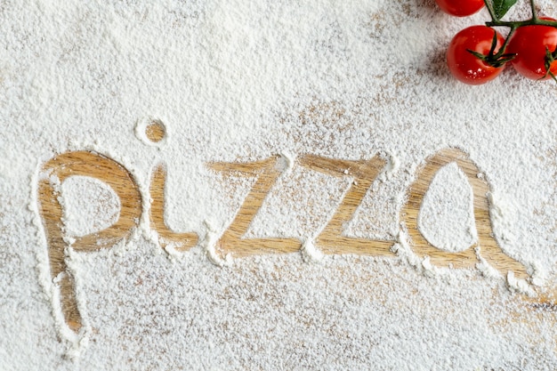 Vista superior de la palabra pizza escrita en harina