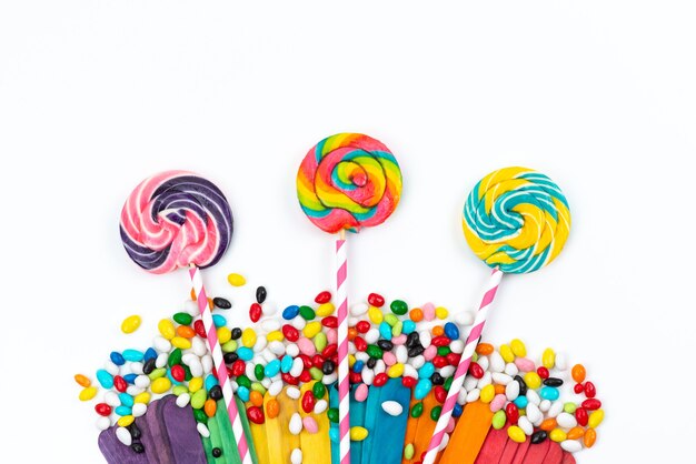 Una vista superior de paletas de colores junto con caramelos en blanco, azúcar de arco iris de colores