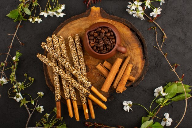 Vista superior de palitos de caramelo junto con canela y semillas de café marrón en el piso oscuro