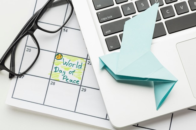 Vista superior de paloma de papel con laptop y día mundial de la paz