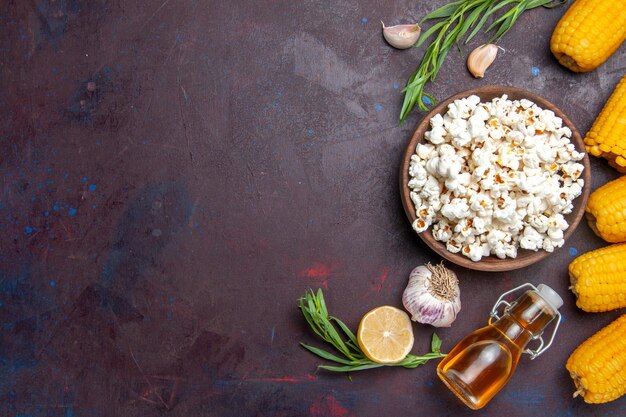 Vista superior de palomitas de maíz frescas con callos amarillos crudos en el maíz de palomitas de maíz de snack de superficie oscura