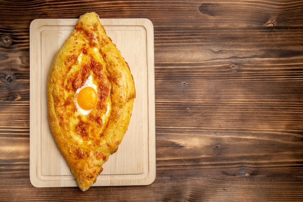 Foto gratuita vista superior de pan horneado con huevo cocido en el escritorio de madera marrón pan bollo comida huevo masa para el desayuno