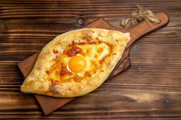 Vista superior de pan horneado con huevo cocido en la superficie de madera desayuno de pan de masa