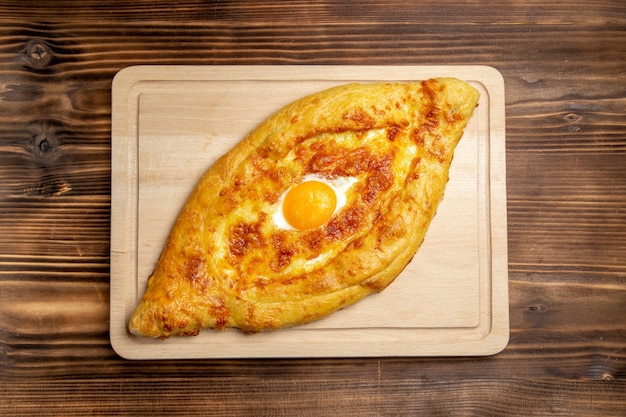 Vista superior de pan horneado con huevo cocido en la superficie de madera pan bollo comida desayuno