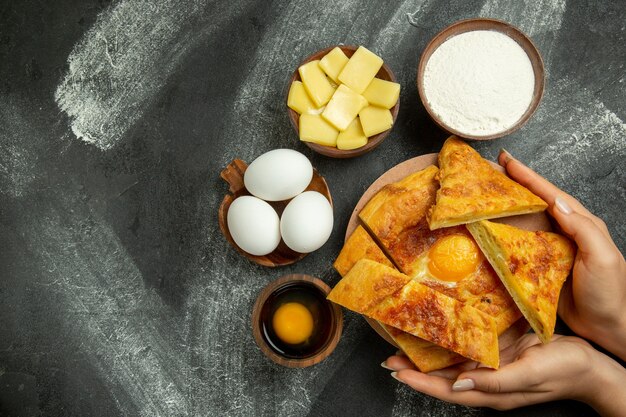 Vista superior de pan de huevo al horno con huevos frescos y queso en rodajas en el escritorio gris