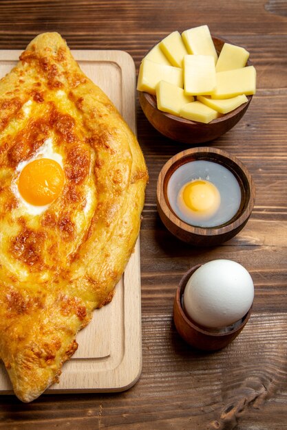 Vista superior de pan recién horneado con huevo cocido en el escritorio de madera marrón masa comida bollo desayuno huevos comida