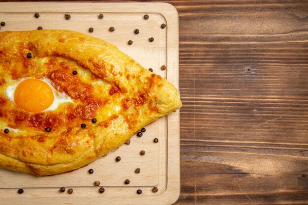 Vista superior de pan recién horneado con huevo cocido en marrón rústico superficie masa desayuno huevo bollo comida comida