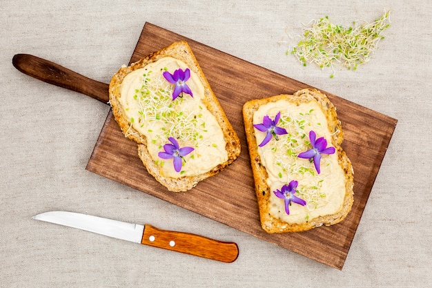 Vista superior de pan tostado con flores en la tabla de cortar