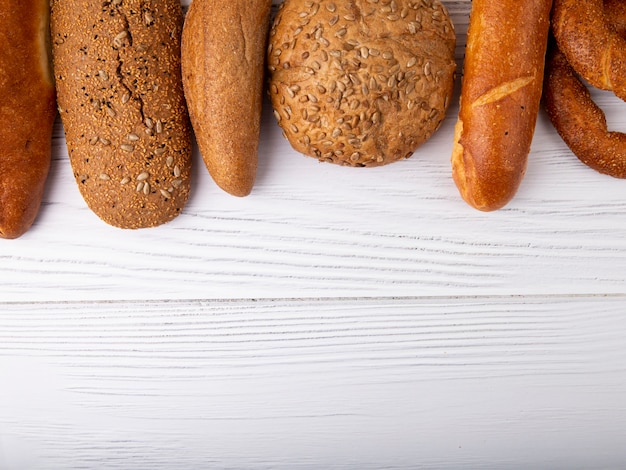 Vista superior de panes como baguette cob bagel sobre fondo de madera con espacio de copia