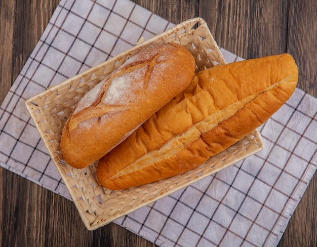 Vista superior de panes como baguette crujiente y vietnamita en la canasta en tela escocesa sobre fondo de madera