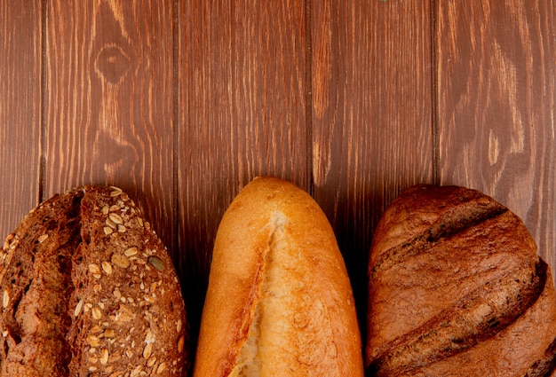 Vista superior de panes como vietnamita y baguette con semillas negras y pan negro en la mesa de madera con espacio de copia