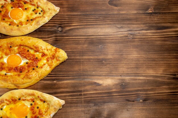 Vista superior panes de huevo horneados recién salidos del horno en un escritorio de madera marrón masa huevos pan bollo desayuno