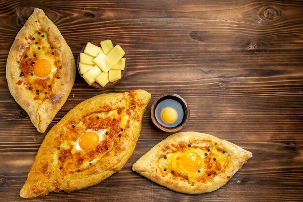 Vista superior panes de huevo horneados recién salidos del horno en un escritorio de madera marrón masa pan bollo desayuno