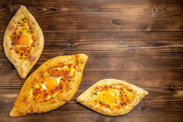 Vista superior de panes de huevo horneados recién salidos del horno en un escritorio de madera marrón, masa, pan de huevo, bollo, desayuno