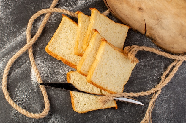 Foto gratuita vista superior de panes de pan blanco en rodajas y sabroso aislado con cuerdas y cuchillo en el fondo gris pan de masa de pan