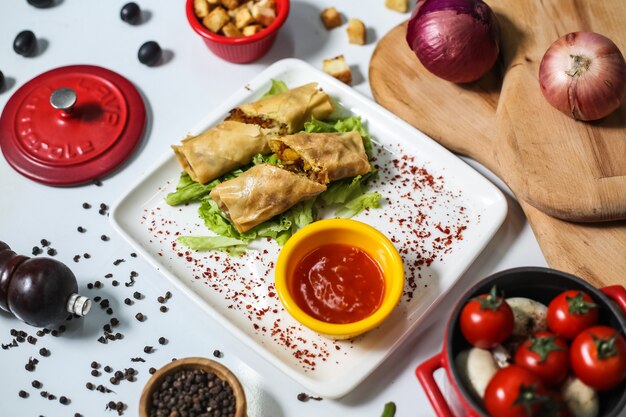 Vista superior de panqueques de carne con salsa de tomate en un plato y tomates, cebollas y champiñones sobre la mesa