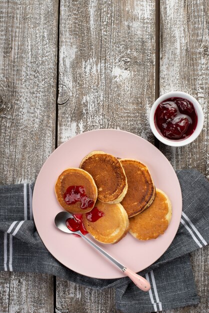 Vista superior de panqueques en un plato para el desayuno con mermelada y cuchara