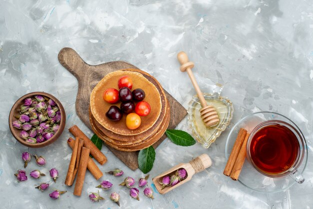 Una vista superior de panqueques redondos horneados y deliciosos con cerezas y fruta de pastel de canela