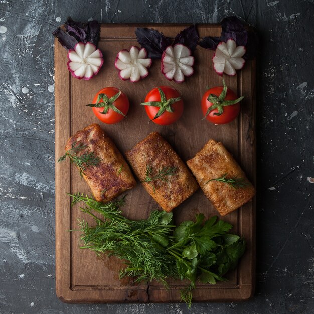 Vista superior de panqueques con verduras y tomate y rábano en tabla de cortar