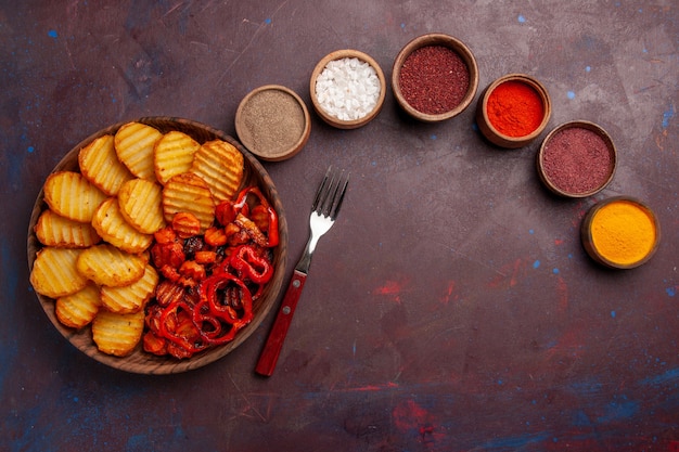 Vista superior de papas al horno con condimentos en un espacio oscuro