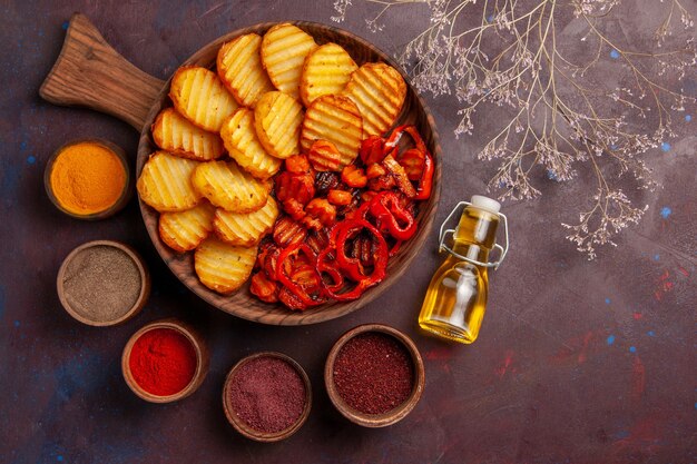 Vista superior de papas al horno con diferentes condimentos en el espacio oscuro