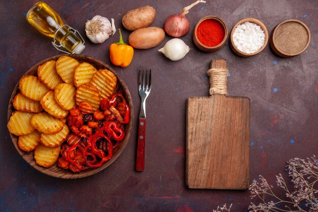 Vista superior de papas al horno con diferentes condimentos en el espacio oscuro