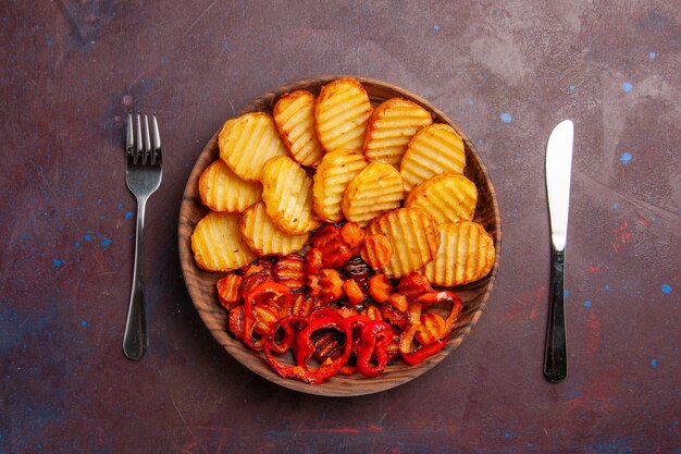 Vista superior de papas al horno con verduras cocidas en el espacio oscuro