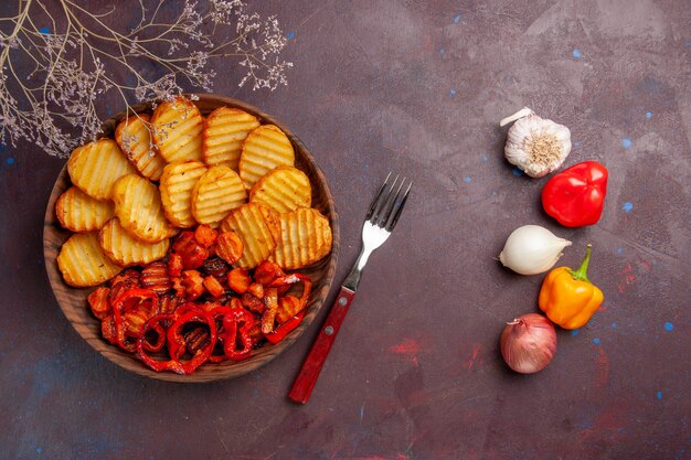 Vista superior de papas al horno con verduras cocidas en el espacio oscuro