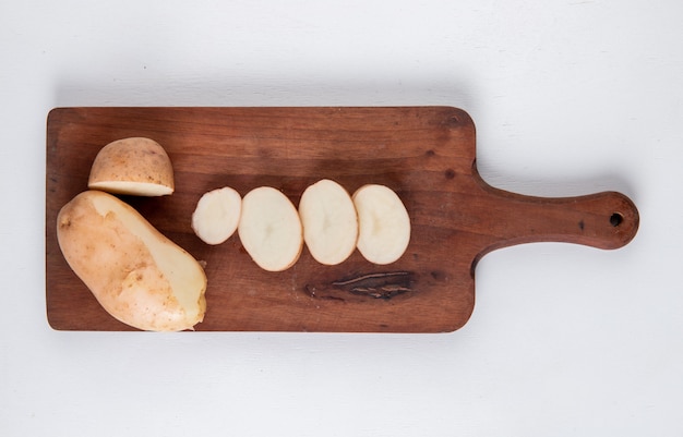 Vista superior de papas cortadas y en rodajas en la tabla de cortar en la superficie blanca