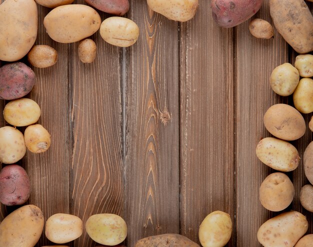 Vista superior de papas enteras en forma circular sobre fondo de madera con espacio de copia