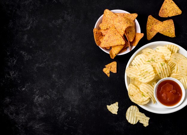 Vista superior de papas fritas y nacho chips con salsa de tomate