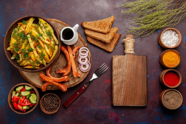 Vista superior de papas fritas con panes de pan de condimentos y diferentes verduras en la superficie oscura